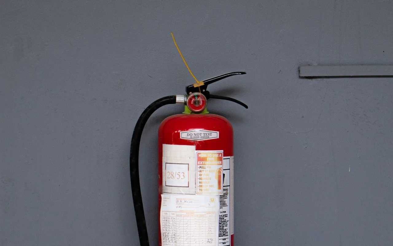 Red fire extinguisher with an inspection service tag mounted against a wall