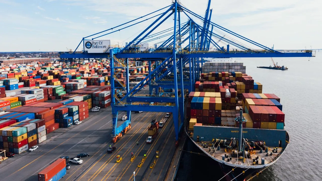 Container ship unloading at a port terminal with stacked shipping containers and gantry cranes