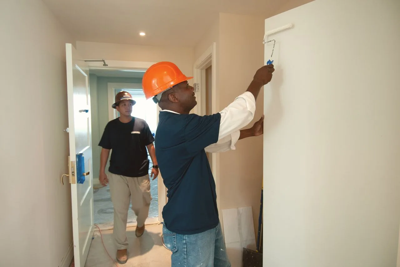 Construction workers in hard hats finishing and painting an interior fit-out