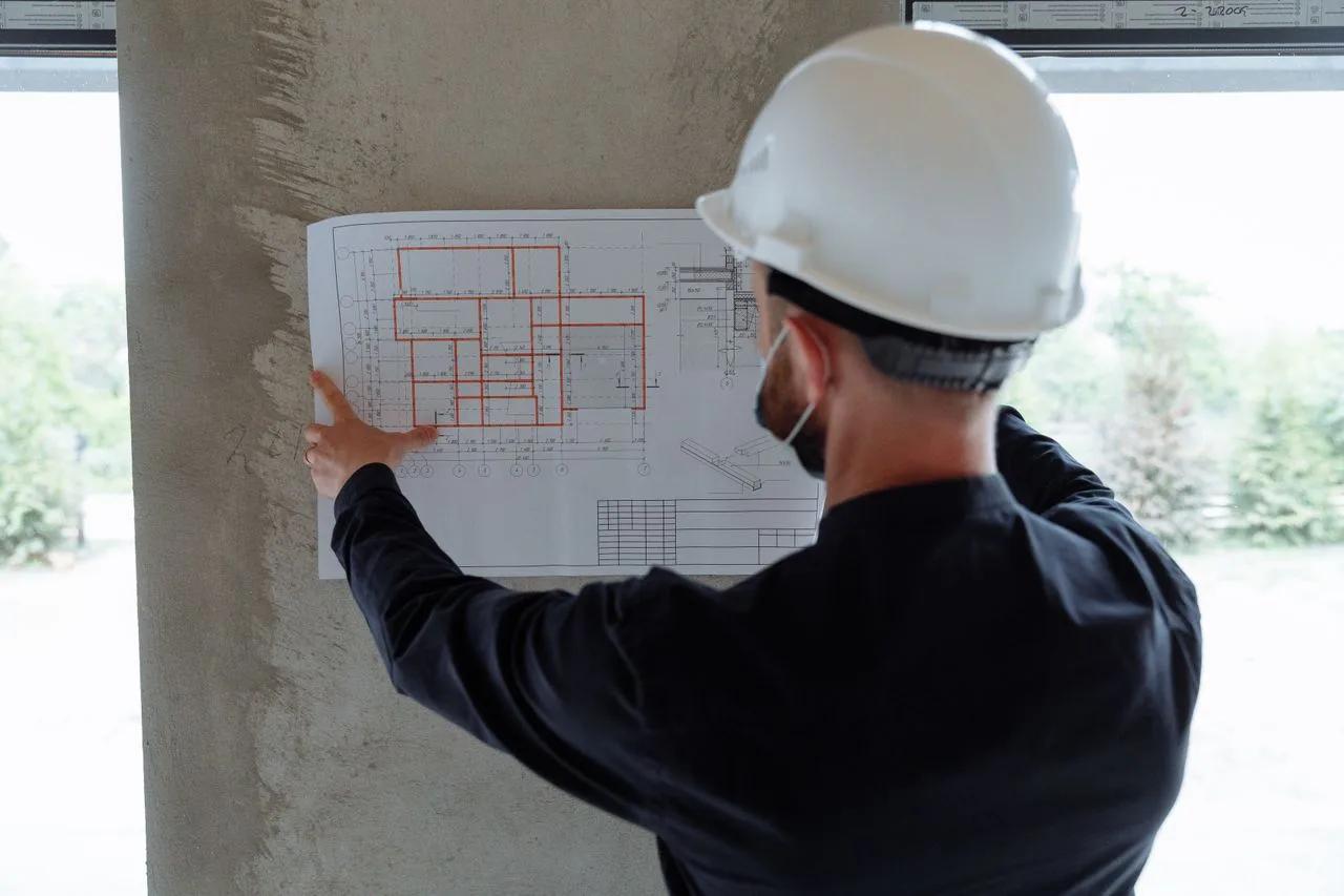 Engineer in a hard hat reviewing a building floor plan on site
